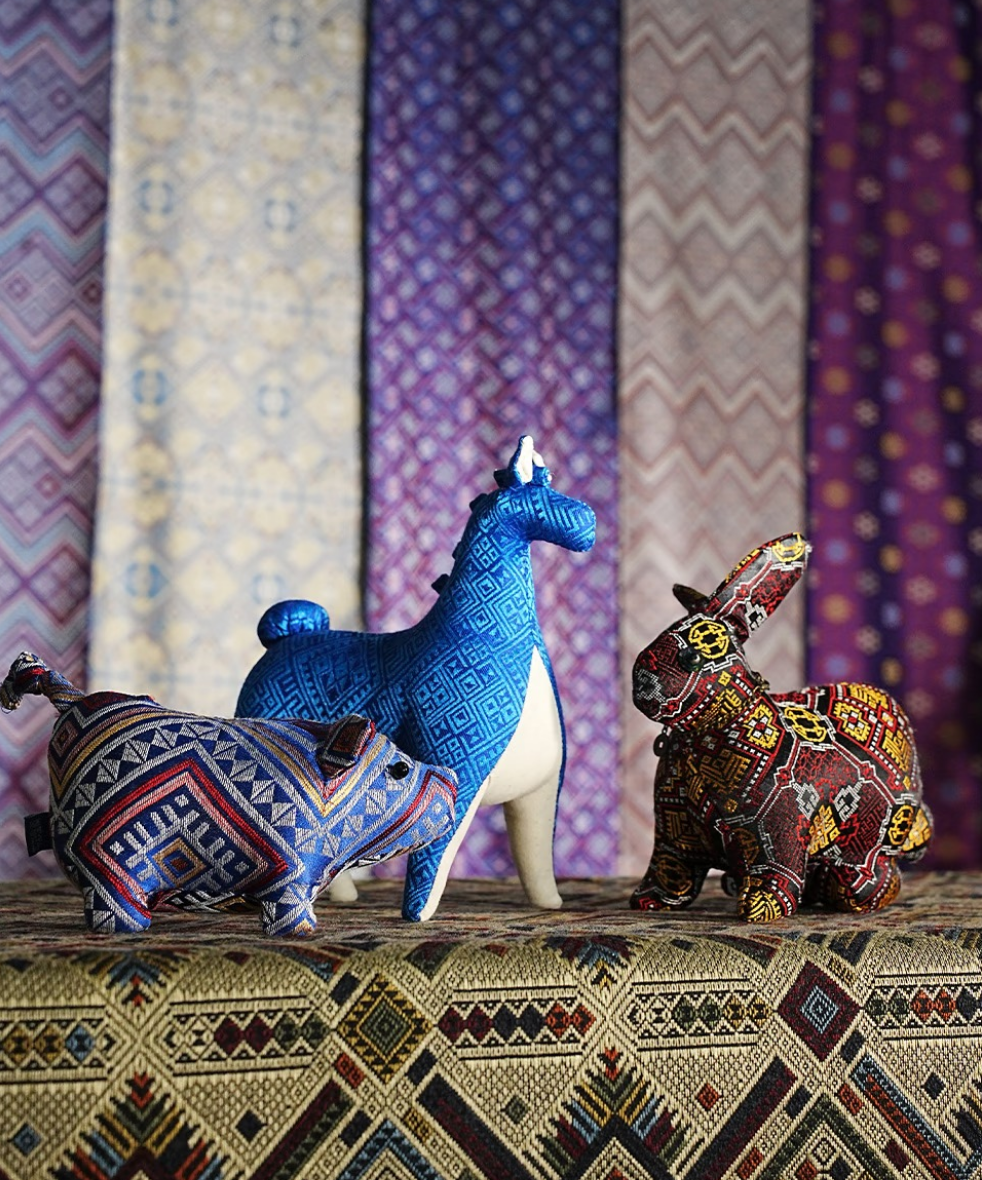 Zhuang brocade animal figures displayed against colorful traditional woven textiles